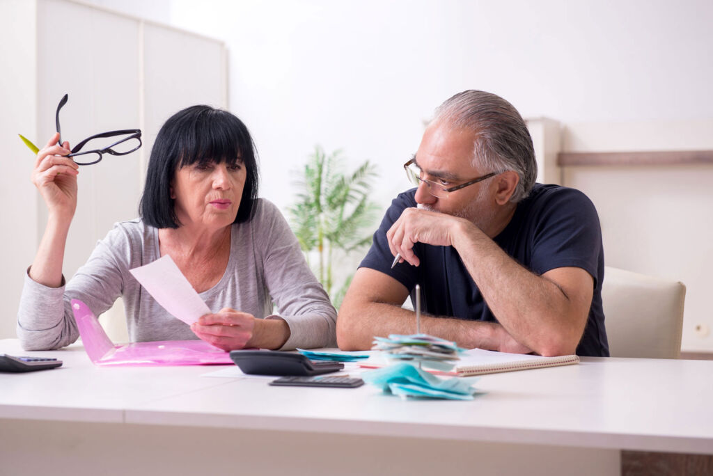 An older couple discussing the rising cost of living, which is evidenced by their bills