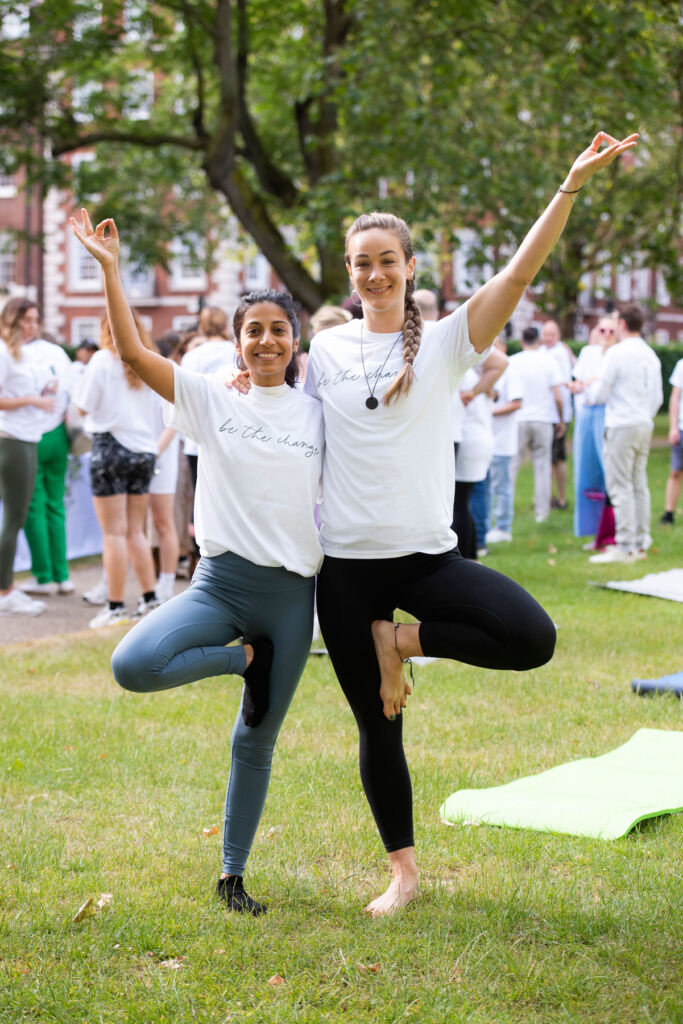 Two young happy ladies doing a joint yoga pose