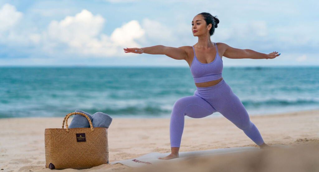 A woman practising yoga by the beach at the resort