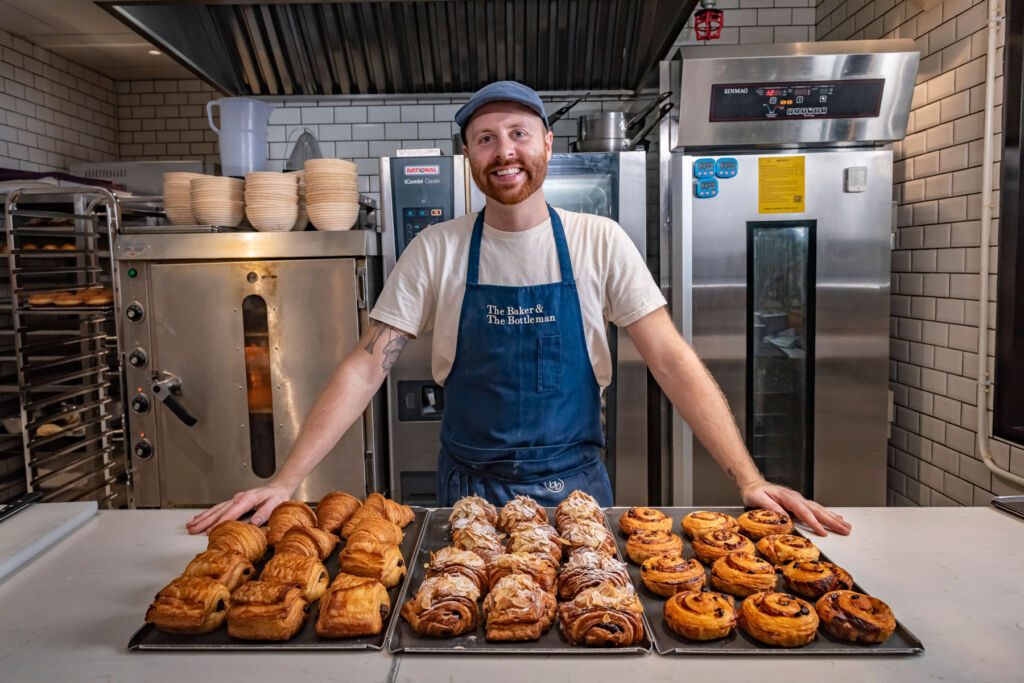 Chef Benjamin Lee standing behind three trays of freshly baked pastries