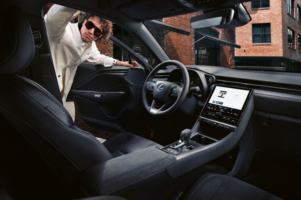 A man with bushy curly hair and sunglasses looking inside the new car