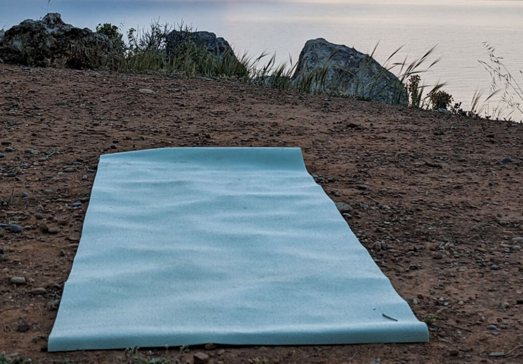Sabi's yoga mat unfurled on the clifftop at sunset