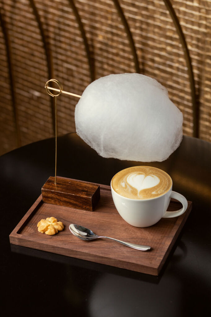 The beautifully presented cloud coffee with a floating cloud above it on a wood and brass frame and a heart in the head of the coffee