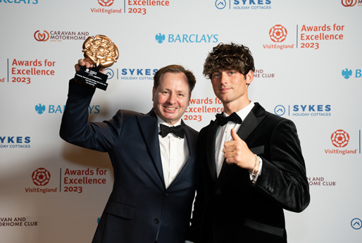 Daniel holding the award aloft accompanied by his son