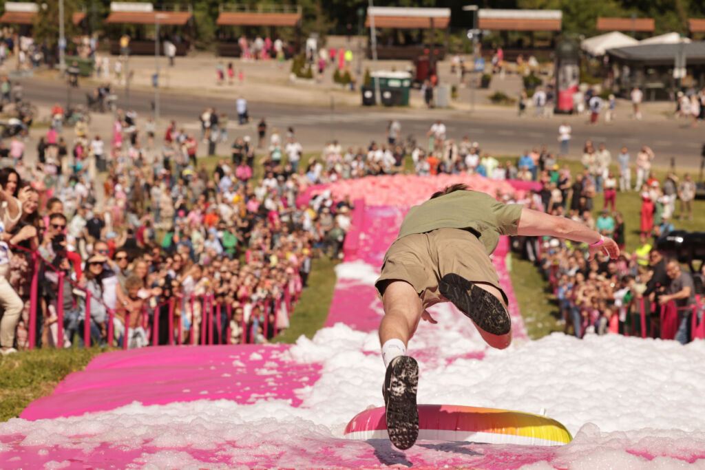 A rear view of a presumably young man diving down the huge slide wearing a pair of shorts