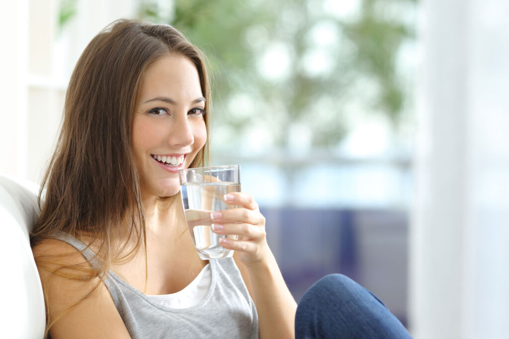 A girl enjoying a glass of clean water in her living room