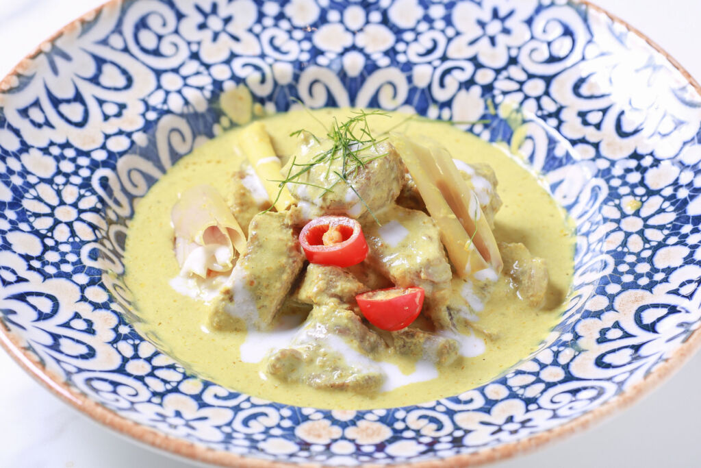Spicy Green Curry with Braised Kamphaeng Saen Beef on a traditional blue and white porcelain dish