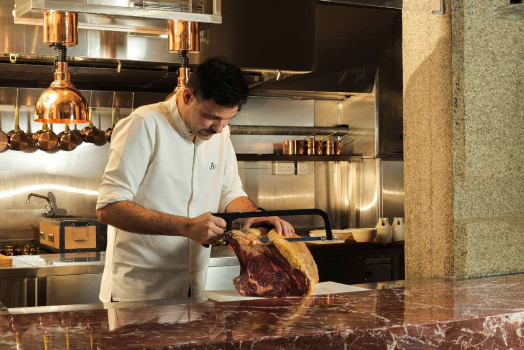 Chef Antonio Oviedo cutting a large slab of meat