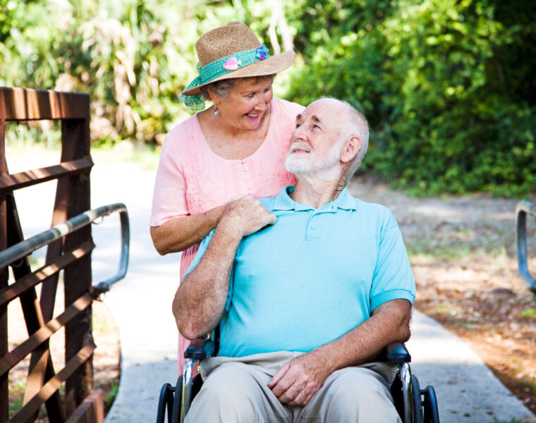 An older woman enjoying the outdoors with her husband who is in a wheelchair