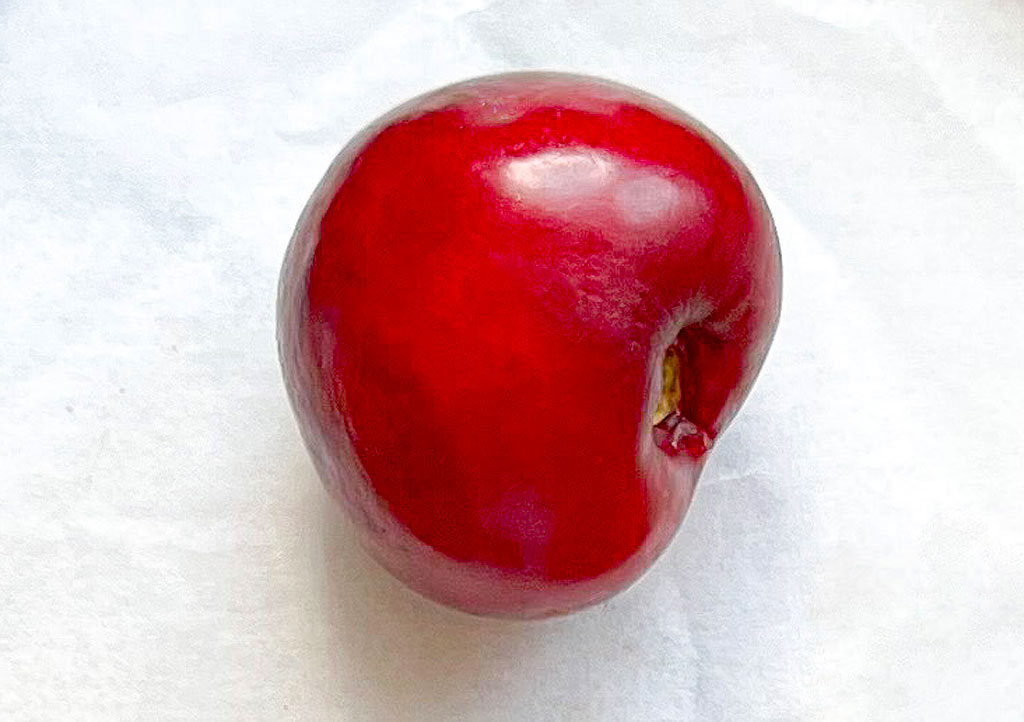 A single cherry on a white table cloth