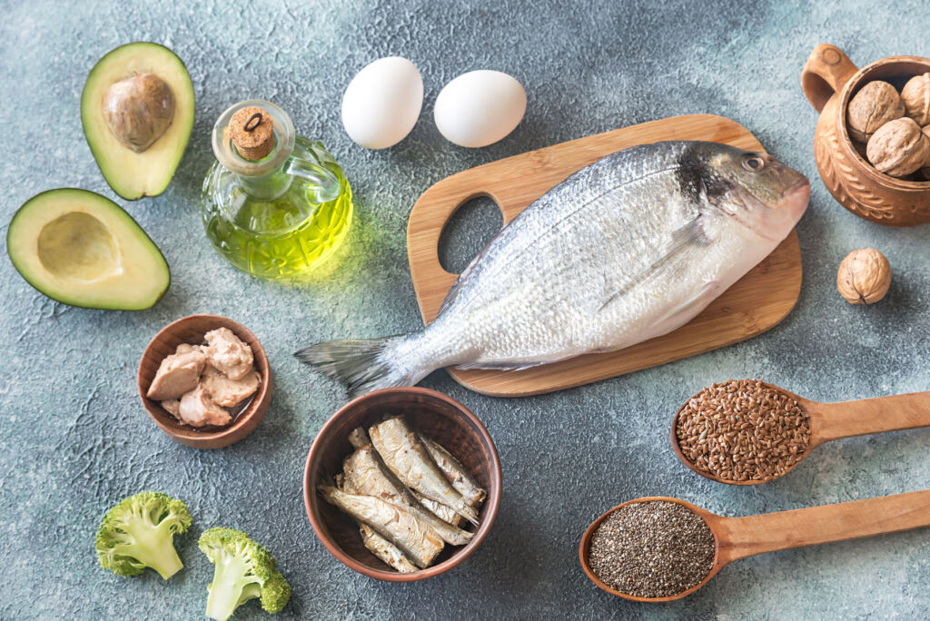 A fish on a wooden chopping board next to a jar of Omega 3 oil