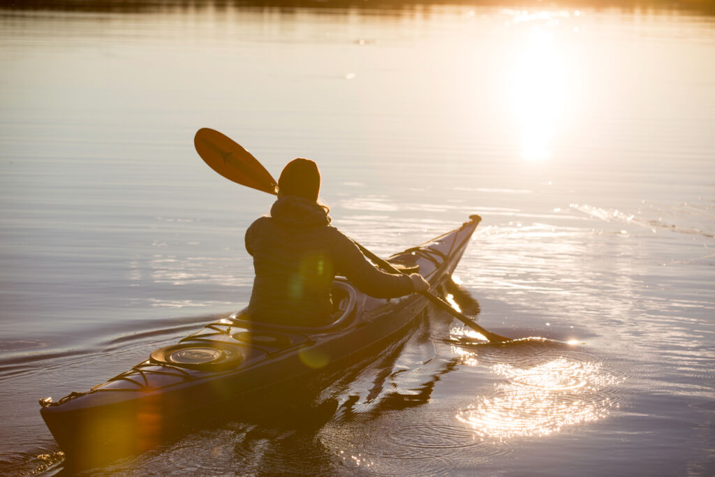 A guest kayaking at sunset