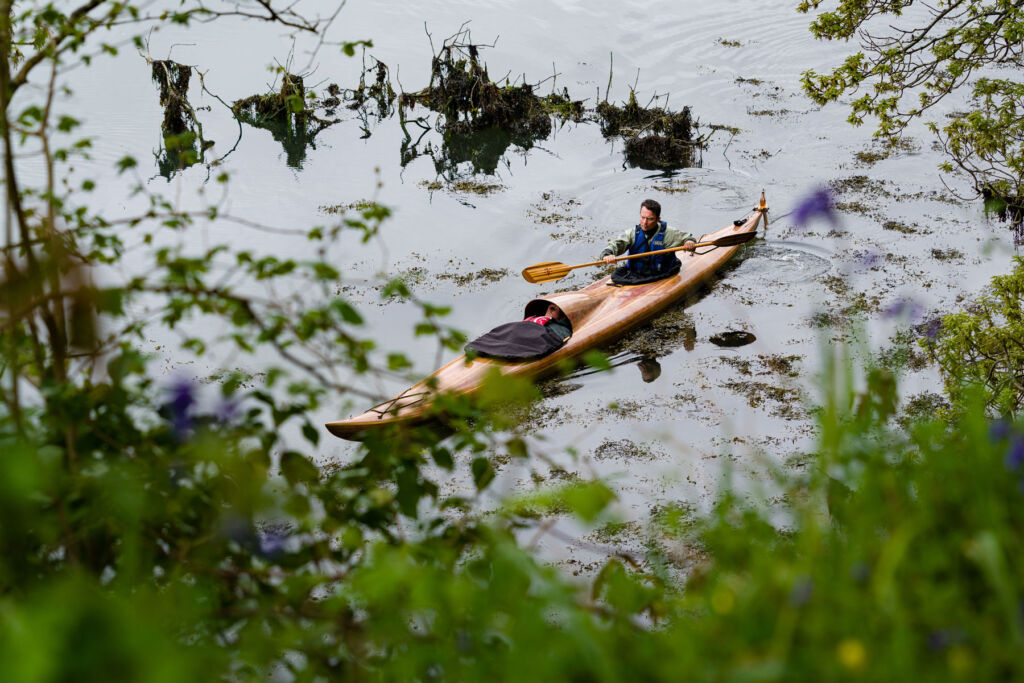 Adam paddling in a wooden canoe