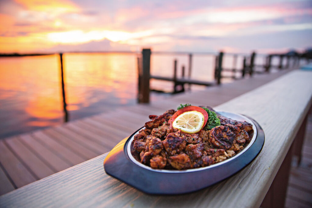 A plate of food on a jetty at sunset