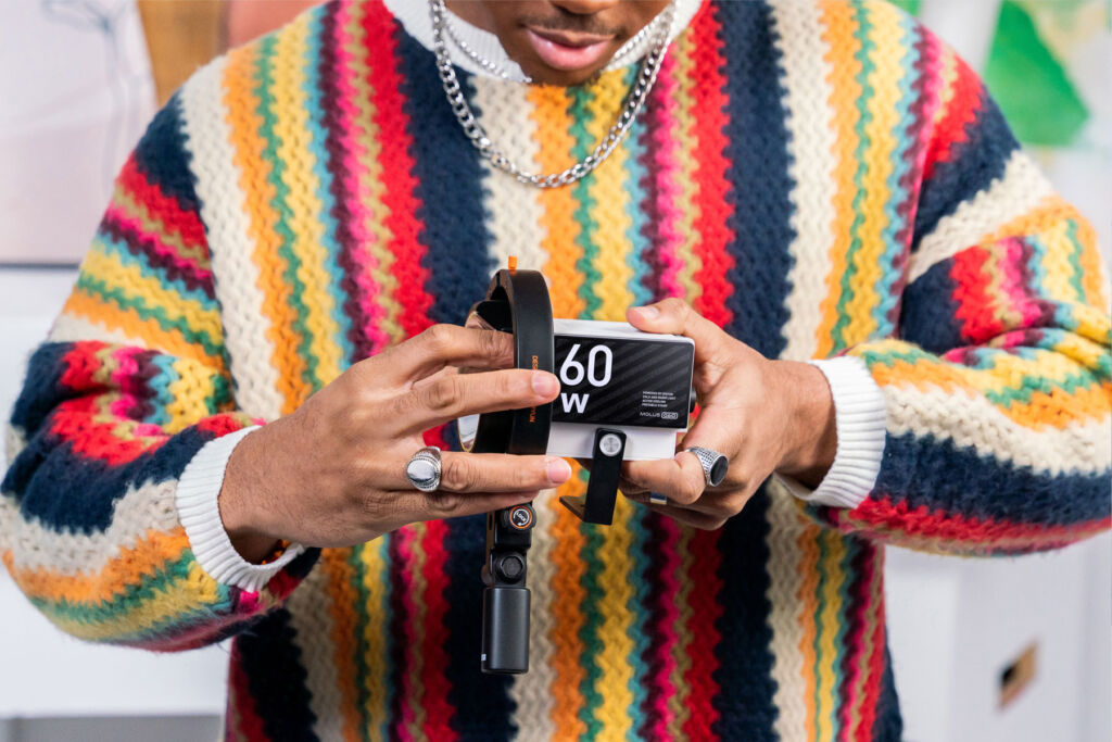 A man wearing a multi-coloured jumper adding an accessory to the light