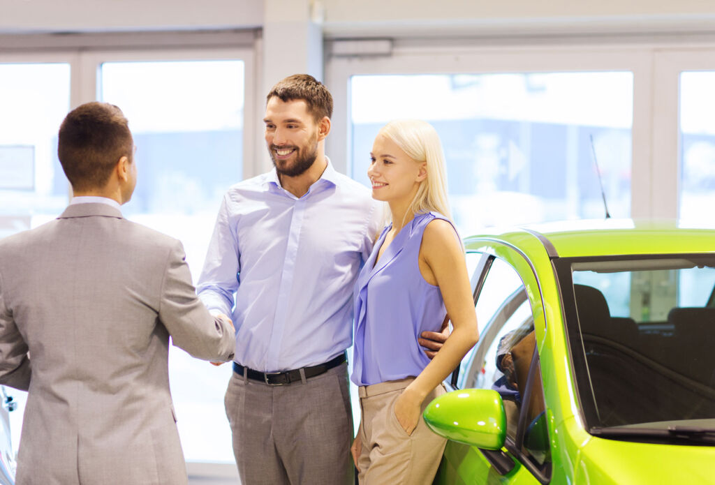 A young couple buying a car from a dealership