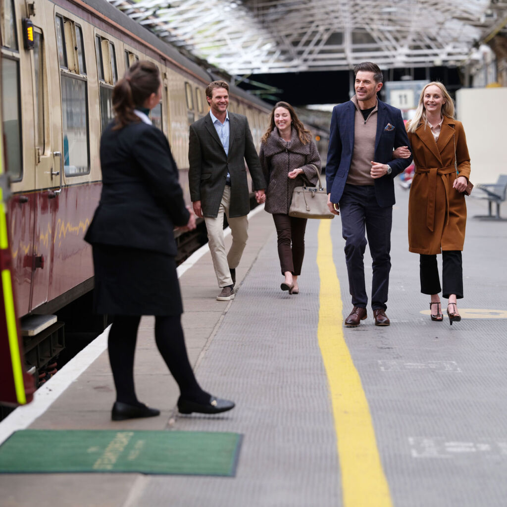 Some of the passengers being greeted by a member of staff before boarding the steam train