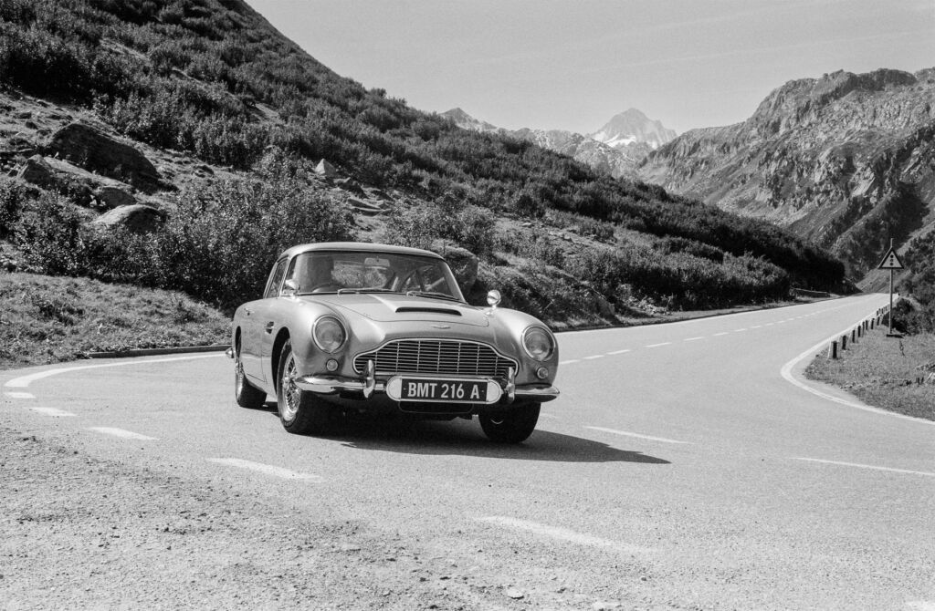 A black and white photo of a DB5 being driven in the mountains