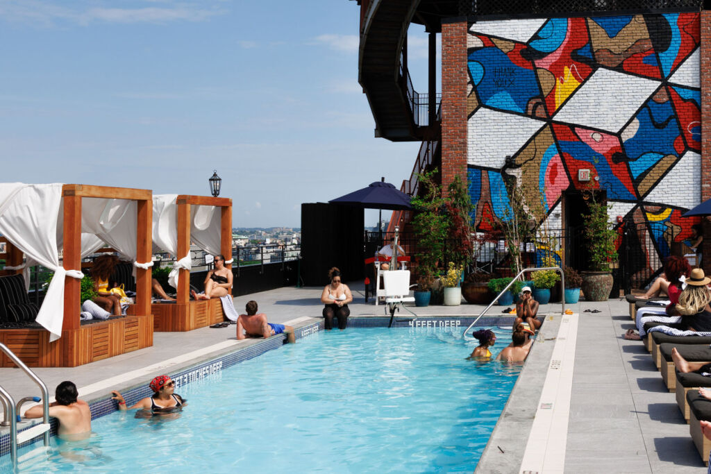 People enjoying the rooftop pool and cabanas