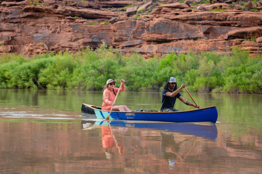 A man and a woman paddling on the water in the blue canoe