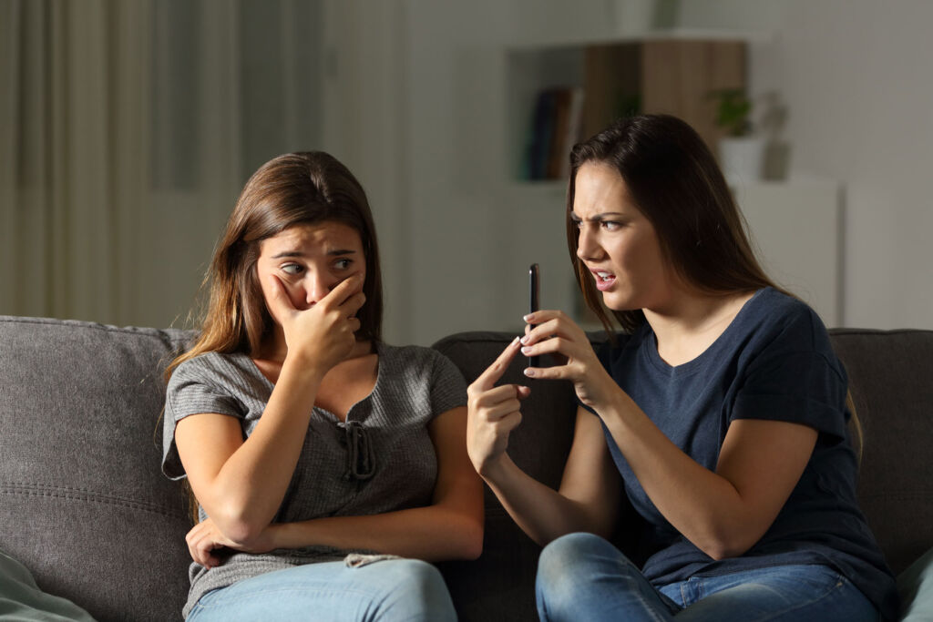 A young girl showing her friend something disturbing on her mobile phone