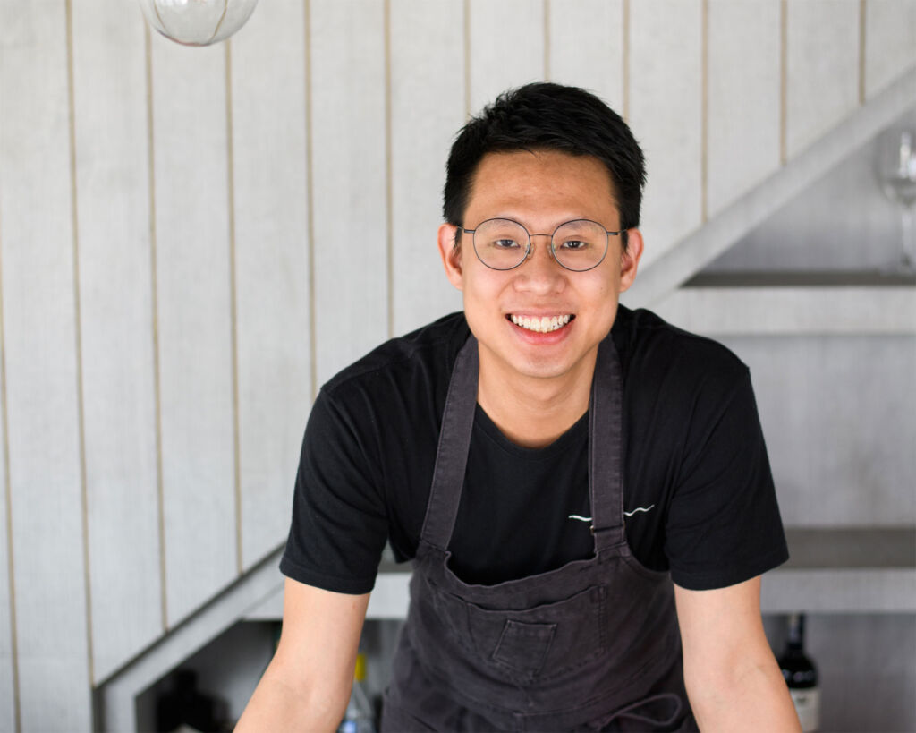 A smiling Chef Johnson Wong leaning on a table