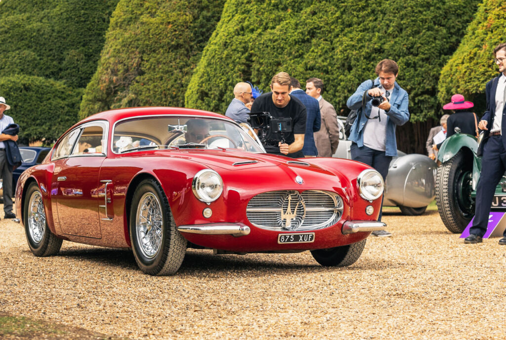 A red coloured vintage Italian sports car being admired