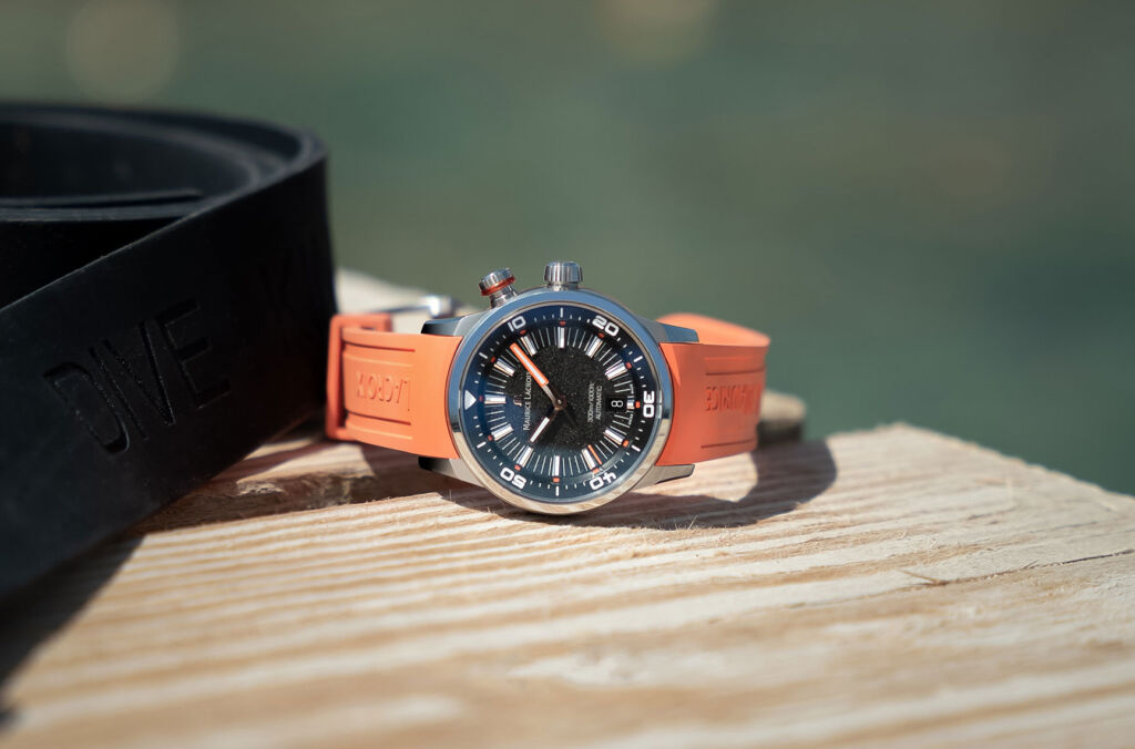 One of the watches with an orange strap laid on a jetty