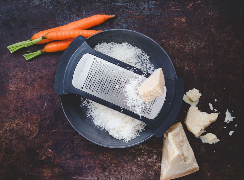 The Bowl Grater Fine Blade cutting through some hard cheese with carrots waiting their turn