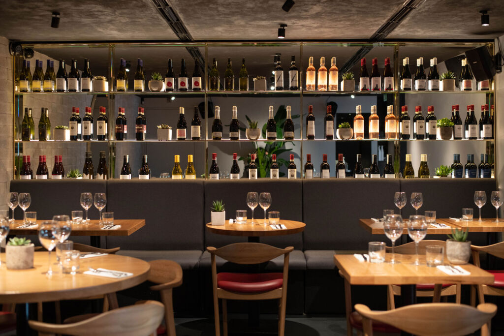 The modern sleek interior with shelves filled with wine bottles by the tables