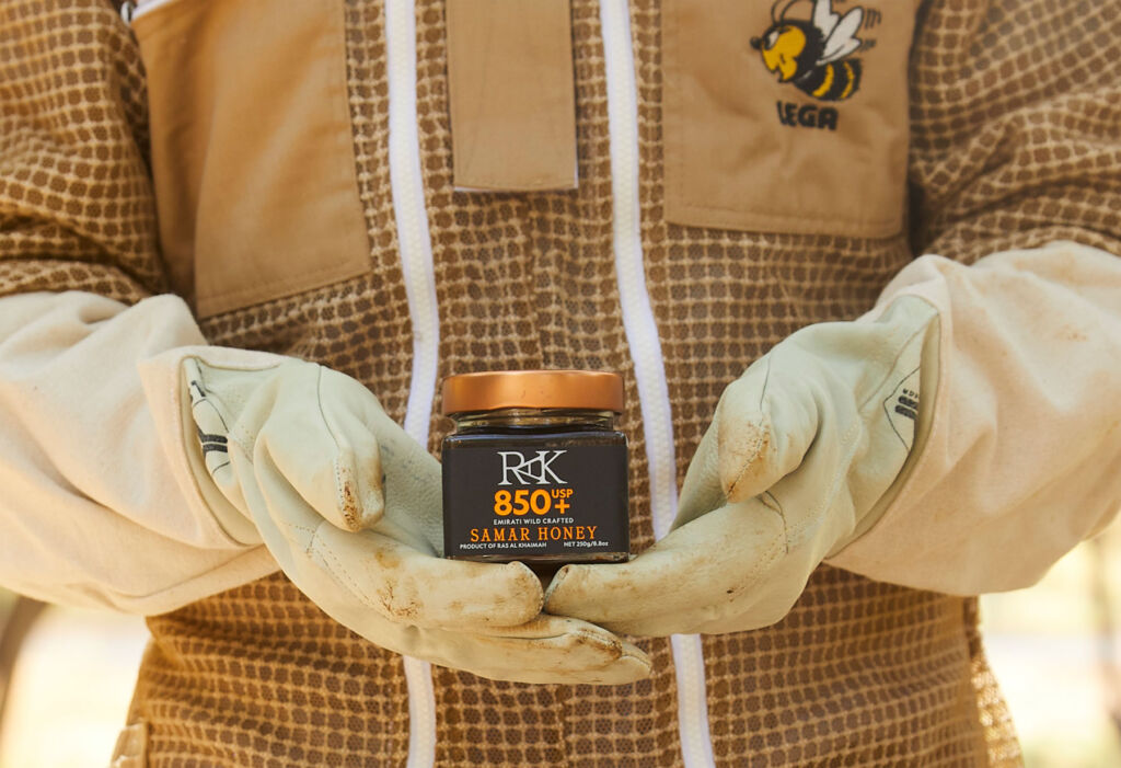 A Beekeeper holding a jar of the honey