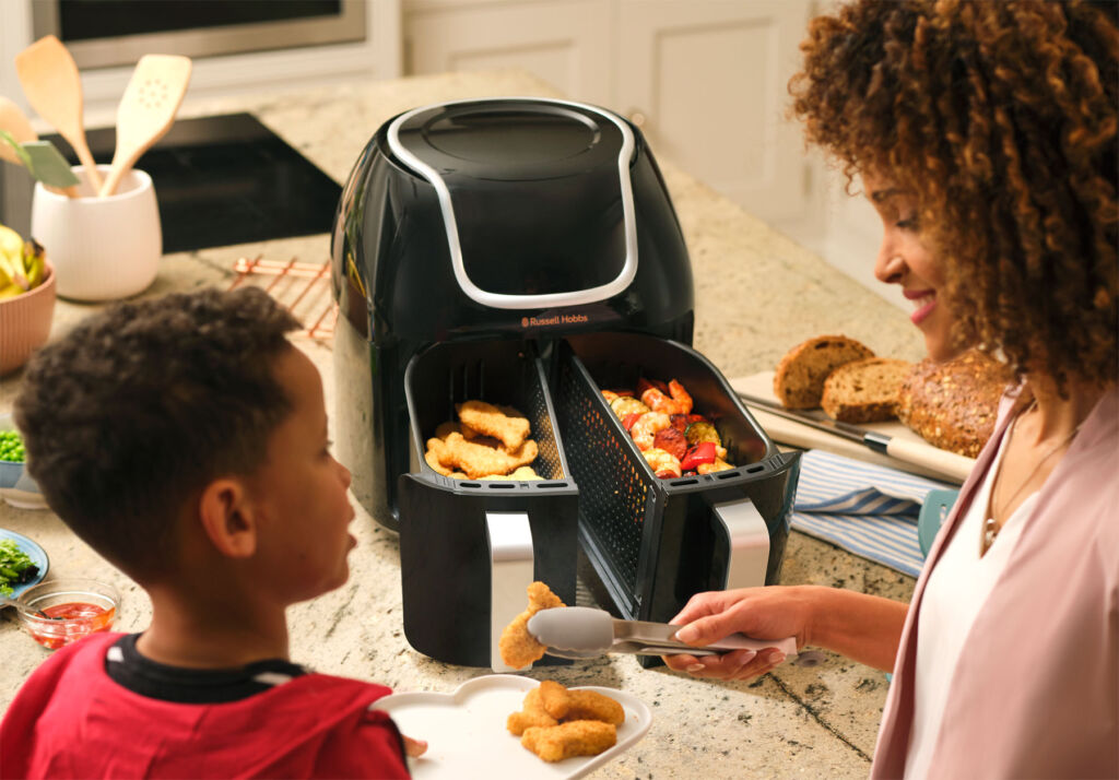 A photograph showing the air fryer cooking different foods in each of its baskets