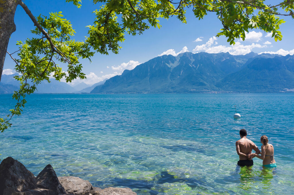 A couple heading into Lake Geneva for a swim