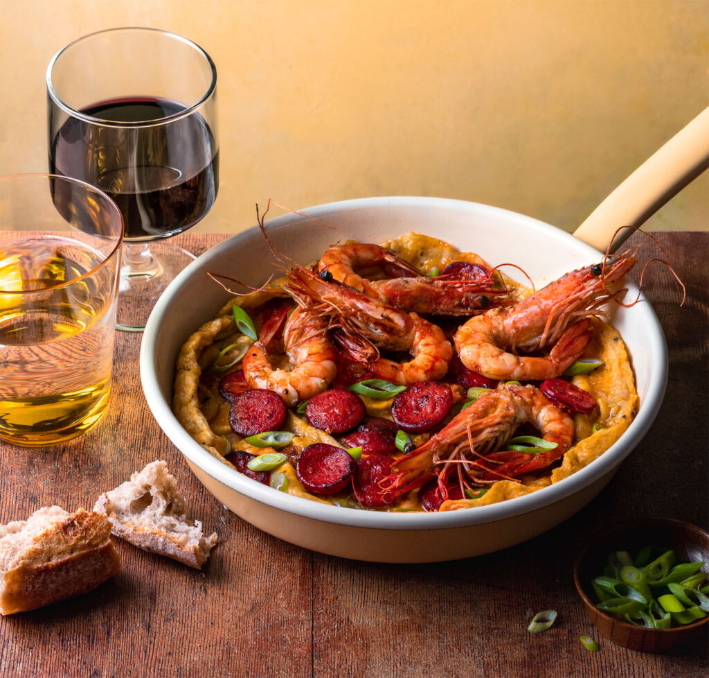 The Consorcio del Chorizo Español Chorizo Open Omelette, Prawns, Spring Onion dish presented in a serving pan next to a glass of red wine