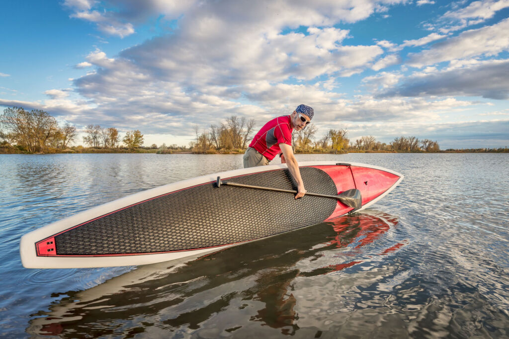 A man taking his paddleboard into the lake