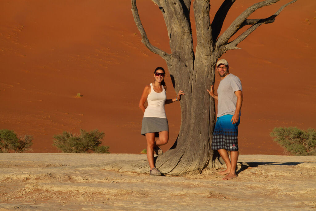 A couple posing by a tree for a photograph o the African plains