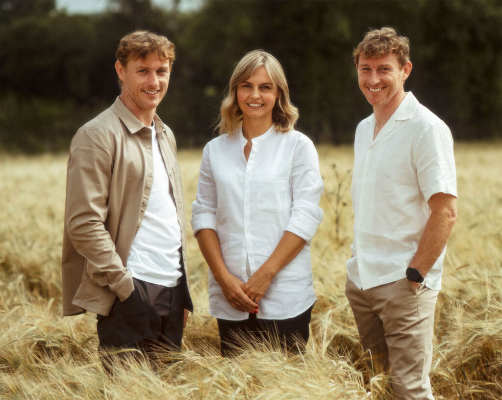 A woman and two men in a field wearing the collaborative clothing