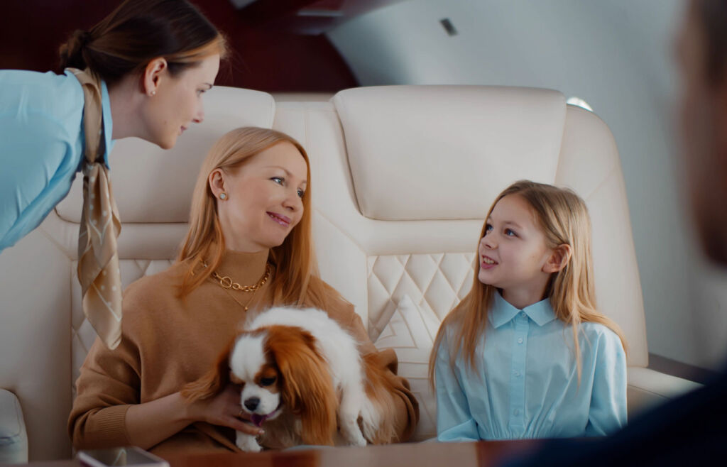 A mum, daughter and their King Charles Spaniel talking to a member of the air crew
