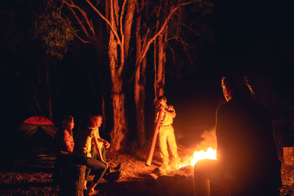 Guests listening to traditional music around a campfire at night