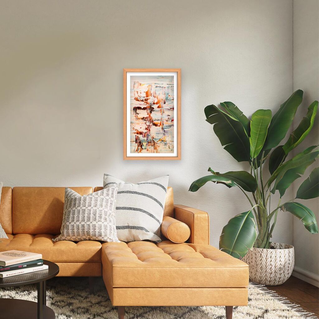 A digital frame hanging on a wall above a sofa and large houseplant