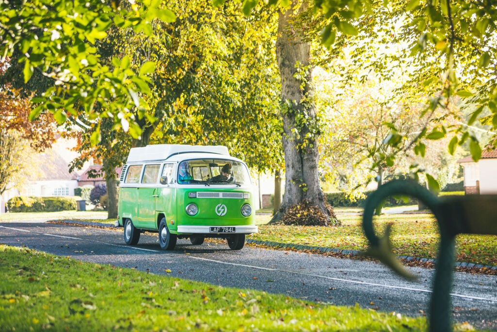 A green VW camper being driven on the road