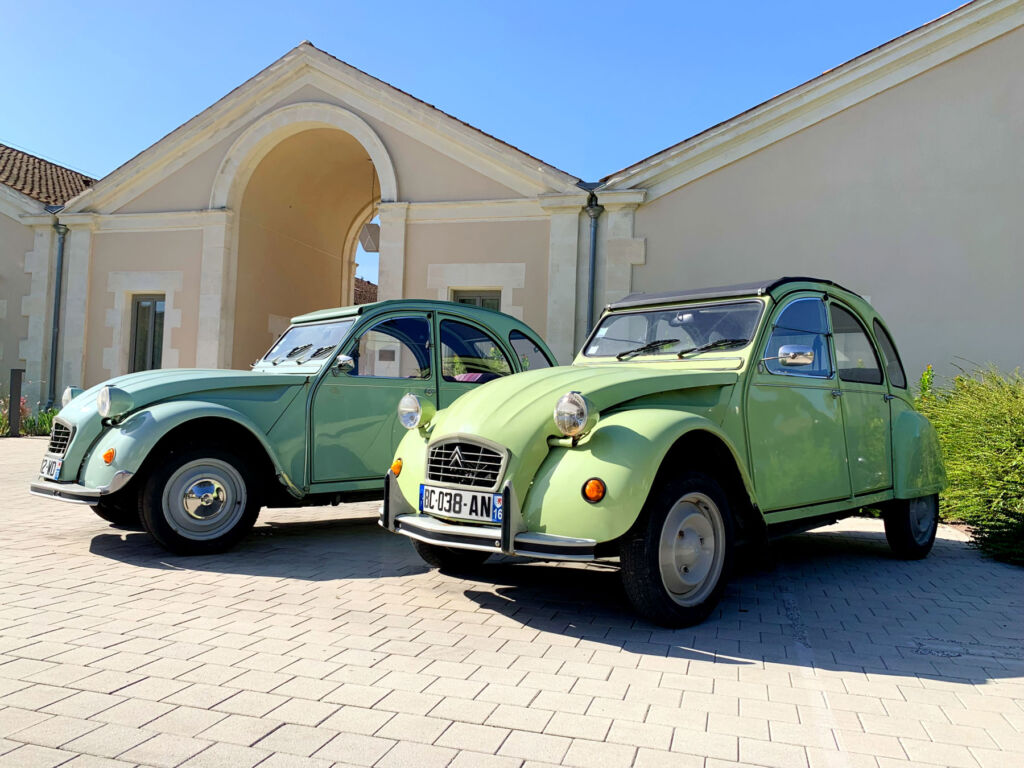 Two green coloured Citroen 2CV cars outside the five-star Hotel, Chais Monnet in Cognac