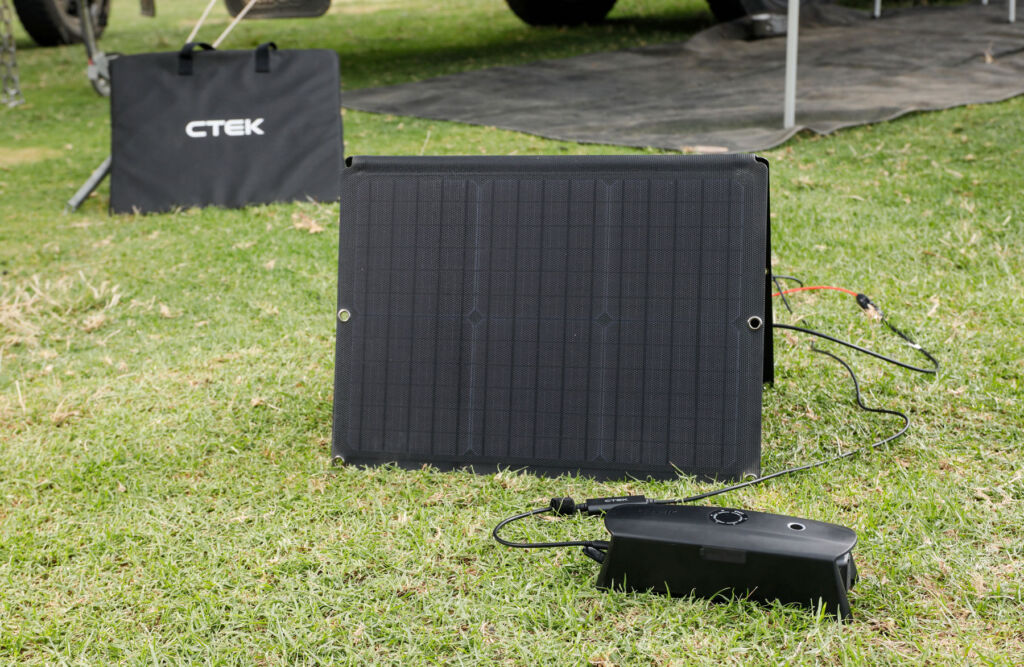 The solar charge kit, the CS FREE and the case for the panel laid out on the grass