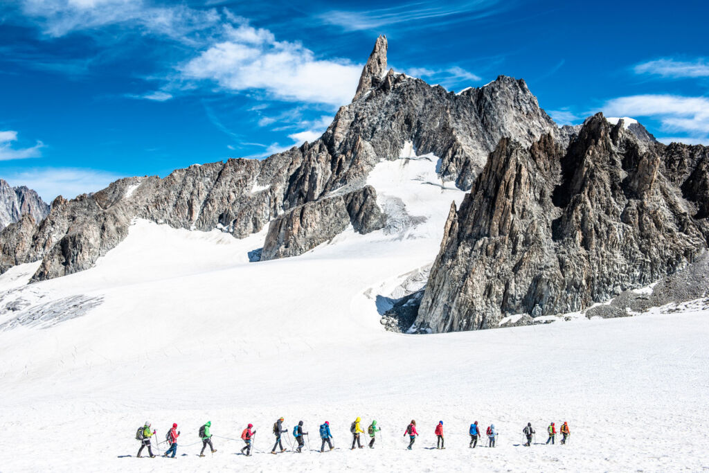 A line of skiers traversing the foot of a mountain