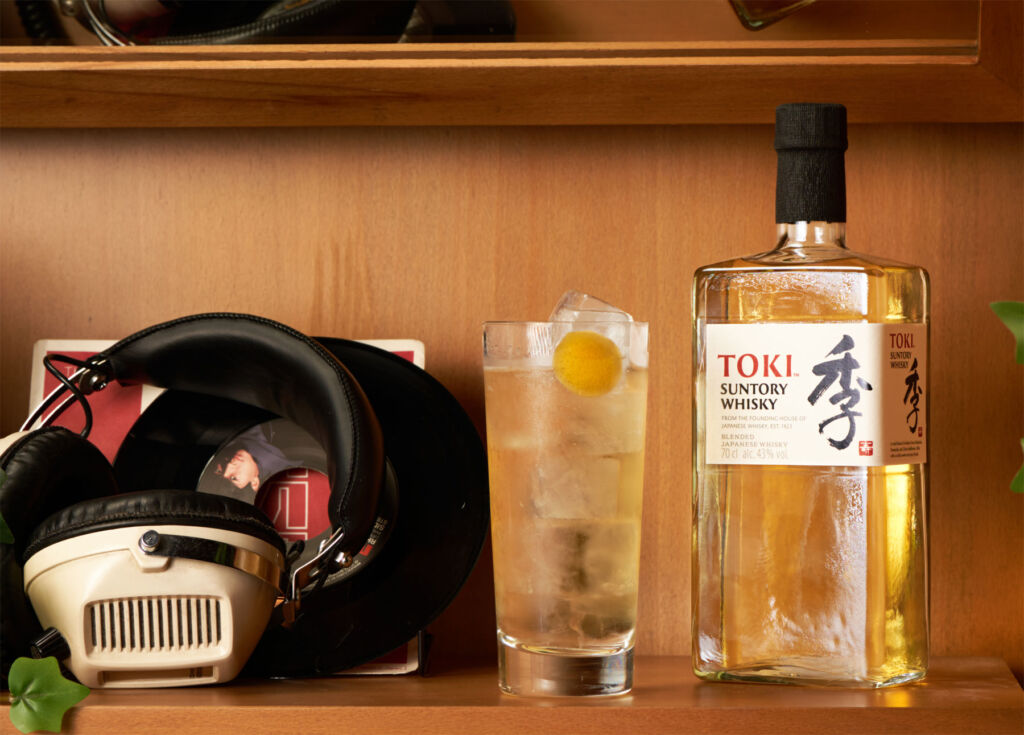 A bottle and cocktail on a shelf next to some headphones