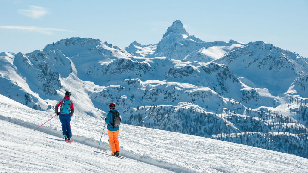 Two skiers pausing for a break before heading down a mountain