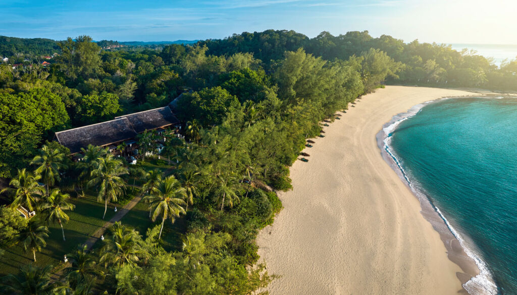 An aerial view showing how the resort blends into the foliage next to the sandy beach