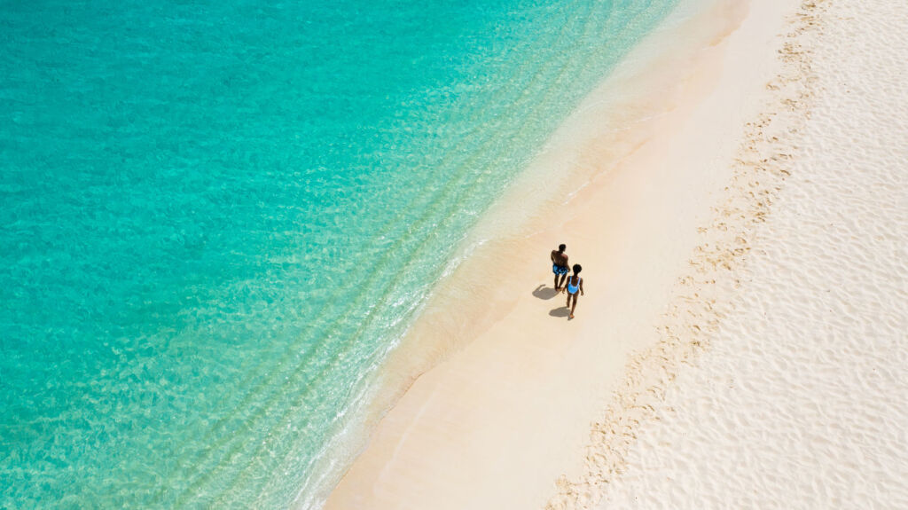 An aerial view of a couple walking on the beach