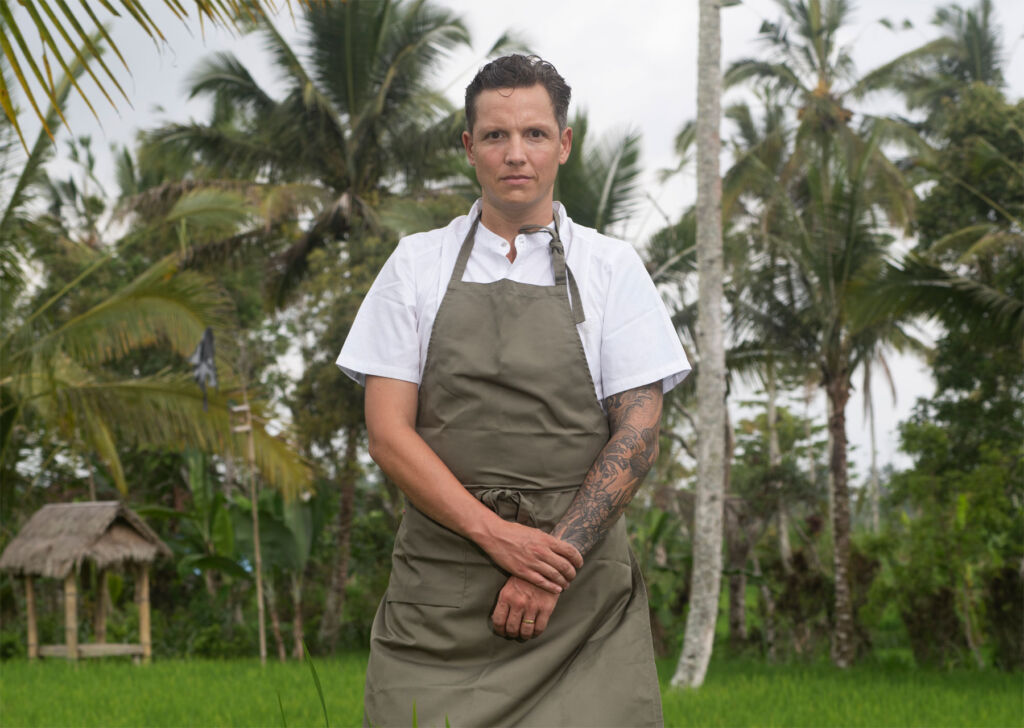 Chef Bakker standing in the Bali countryside in front of a thatched building