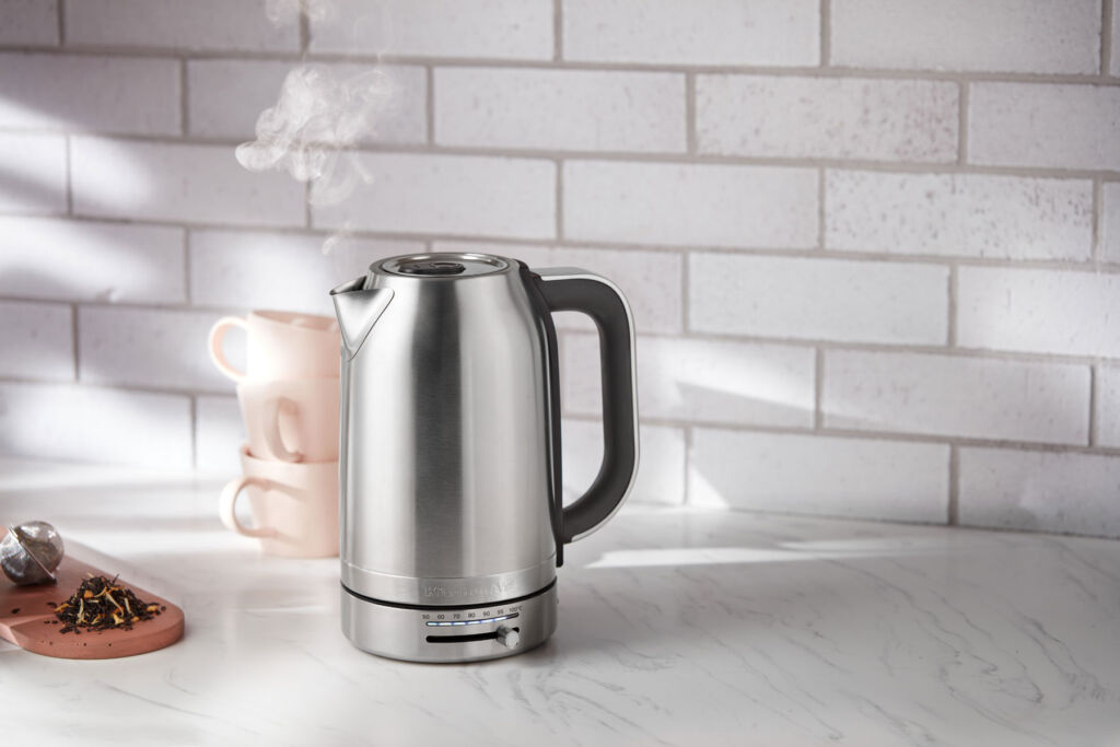 The kettle on a kitchen work surface with steam coming out of its spout